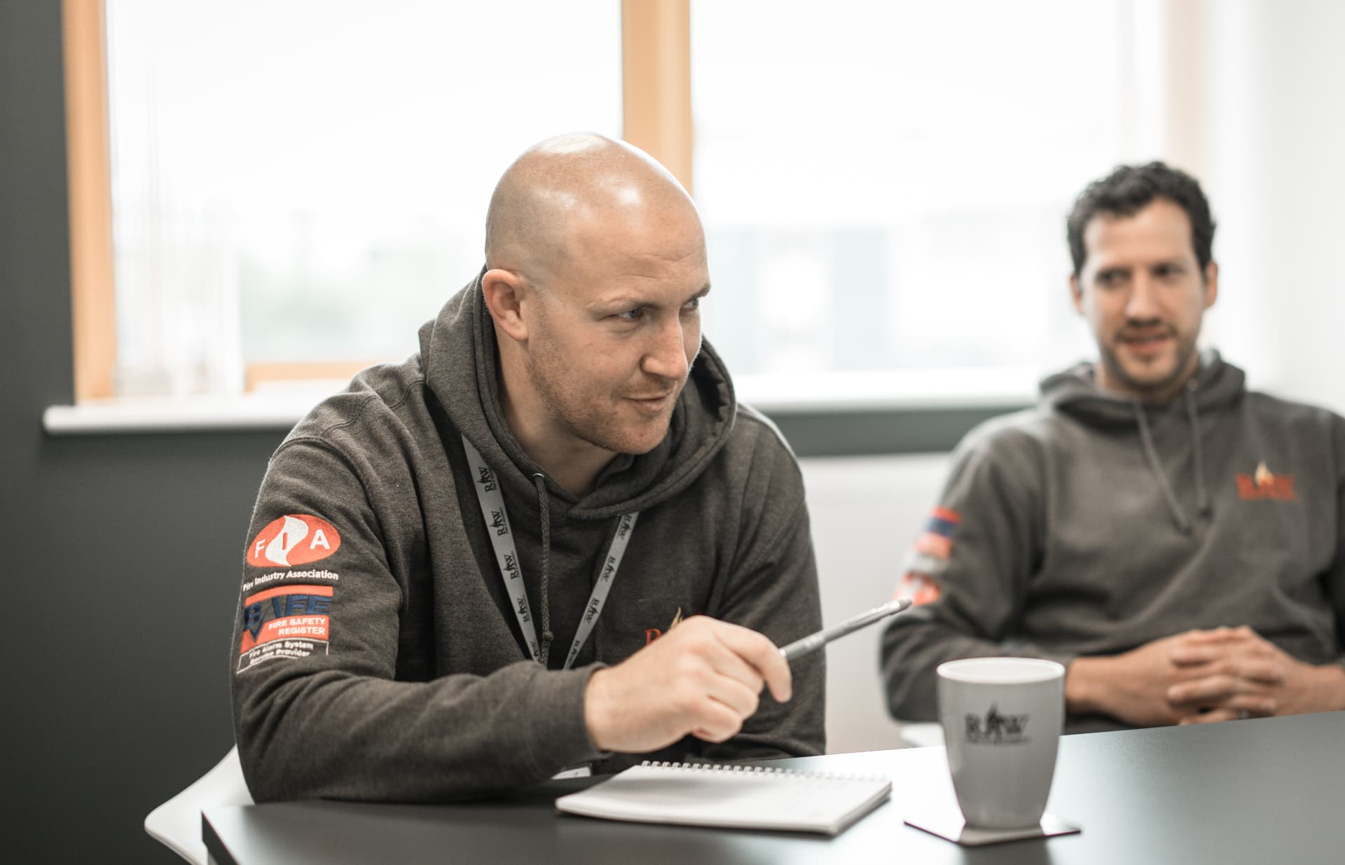 RAW engineer in a BAFE and FIA badged hoodie leading a site discussion